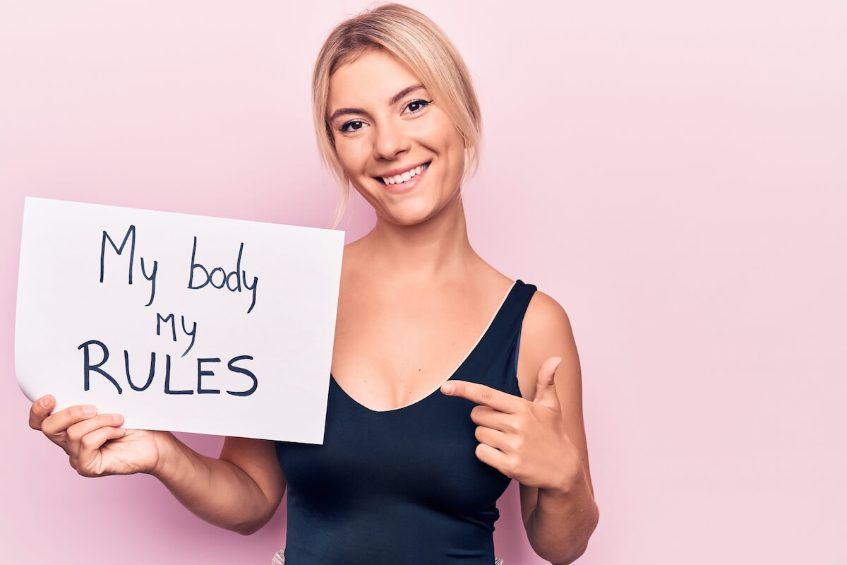 woman holding up sign that says my body my rules.