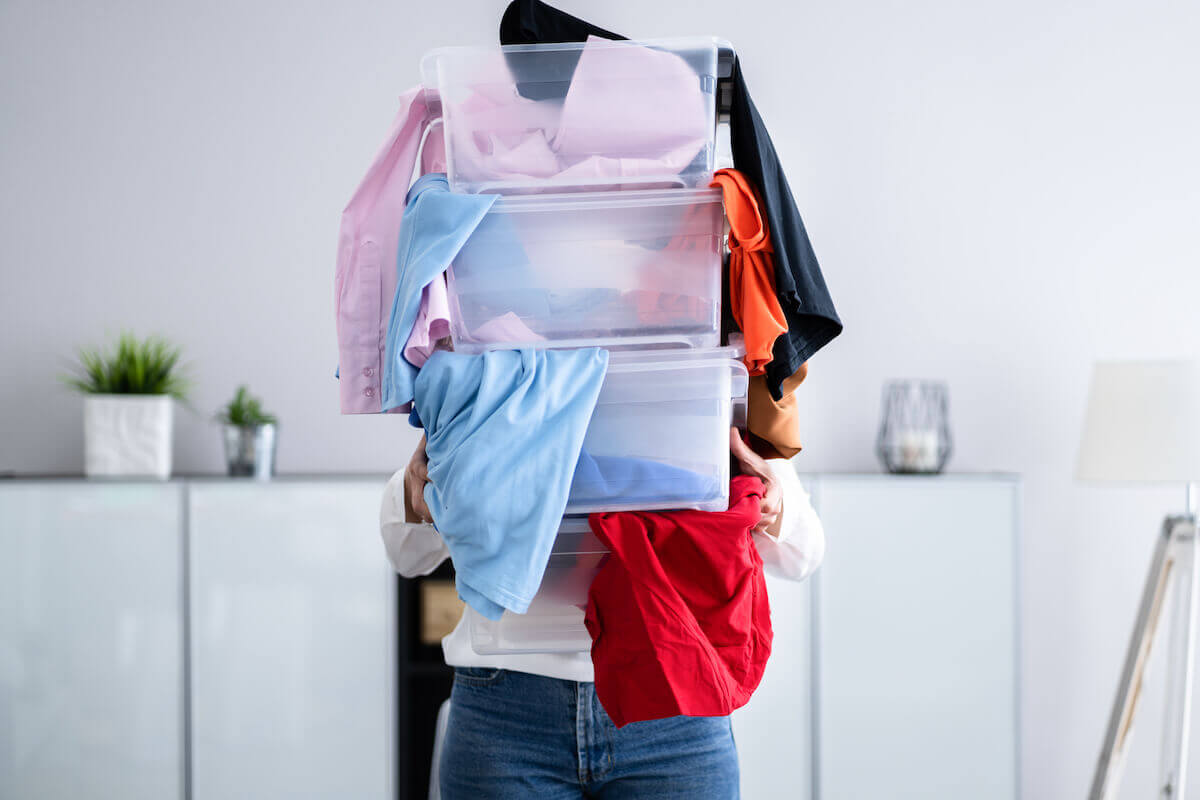 a woman decluttering items from her home, with tubs of unwanted clothes.