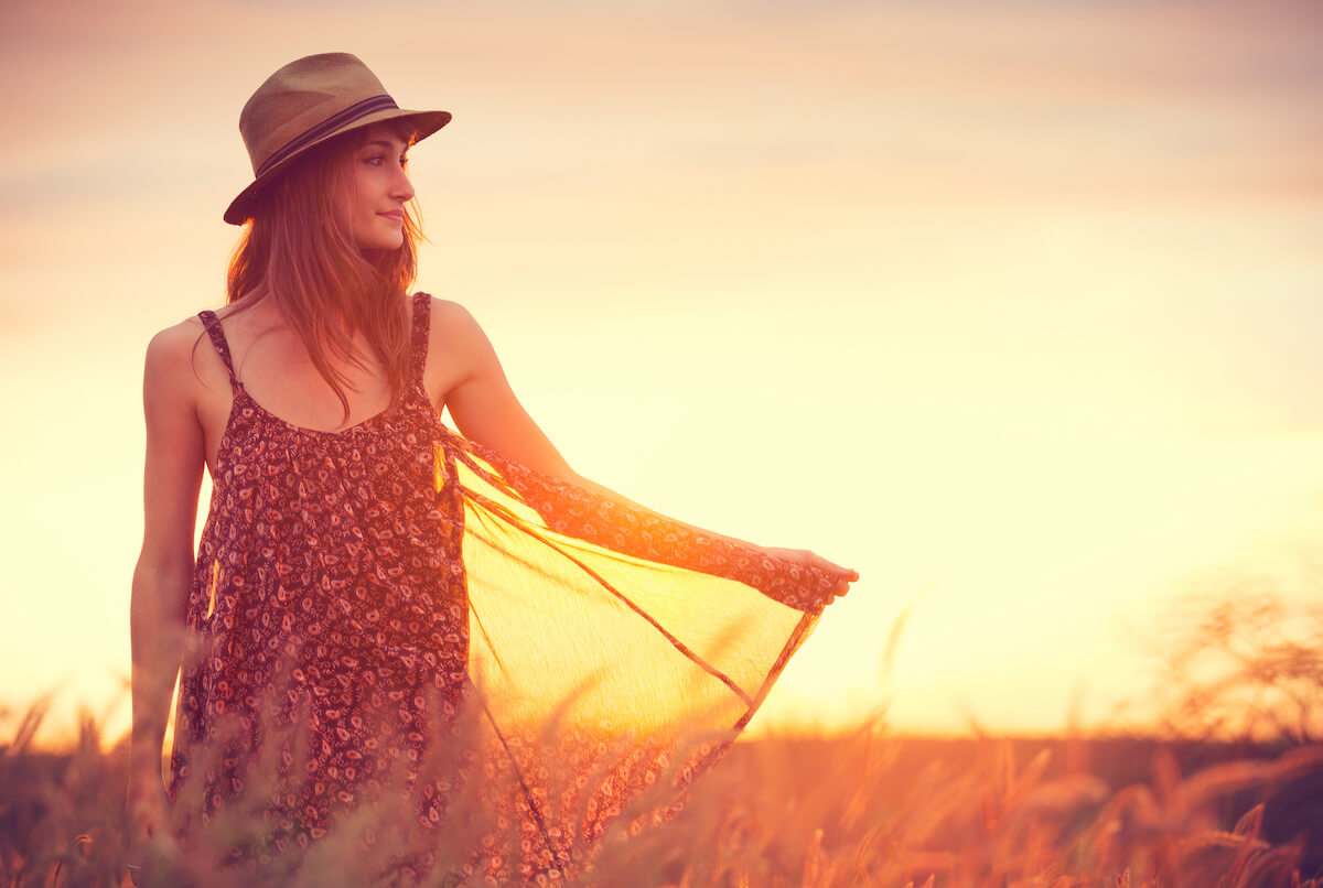 woman twirling her dress around a field at sunset