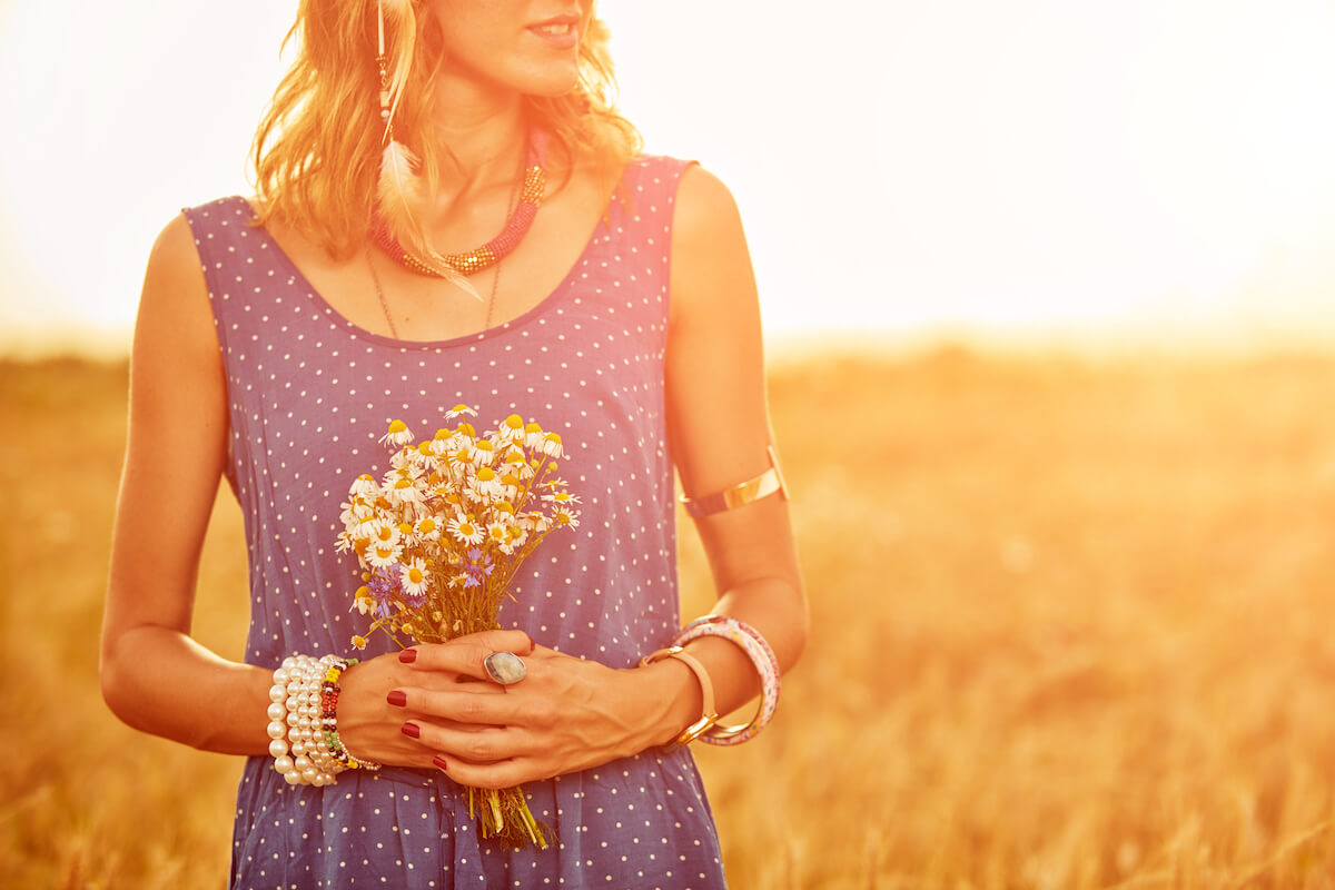 woman standing in field holding a bunch of flowers.
