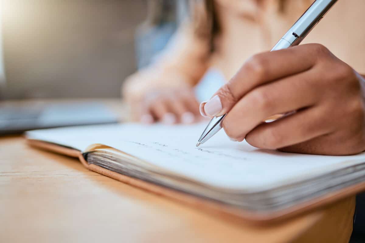 woman writing in a journal with a pen in hand.