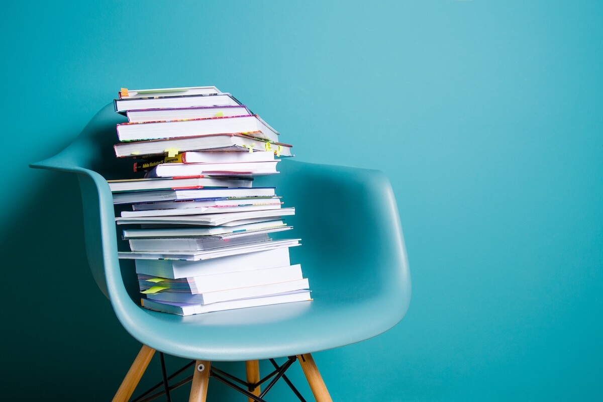 stack on books on blue chair with blue walls.