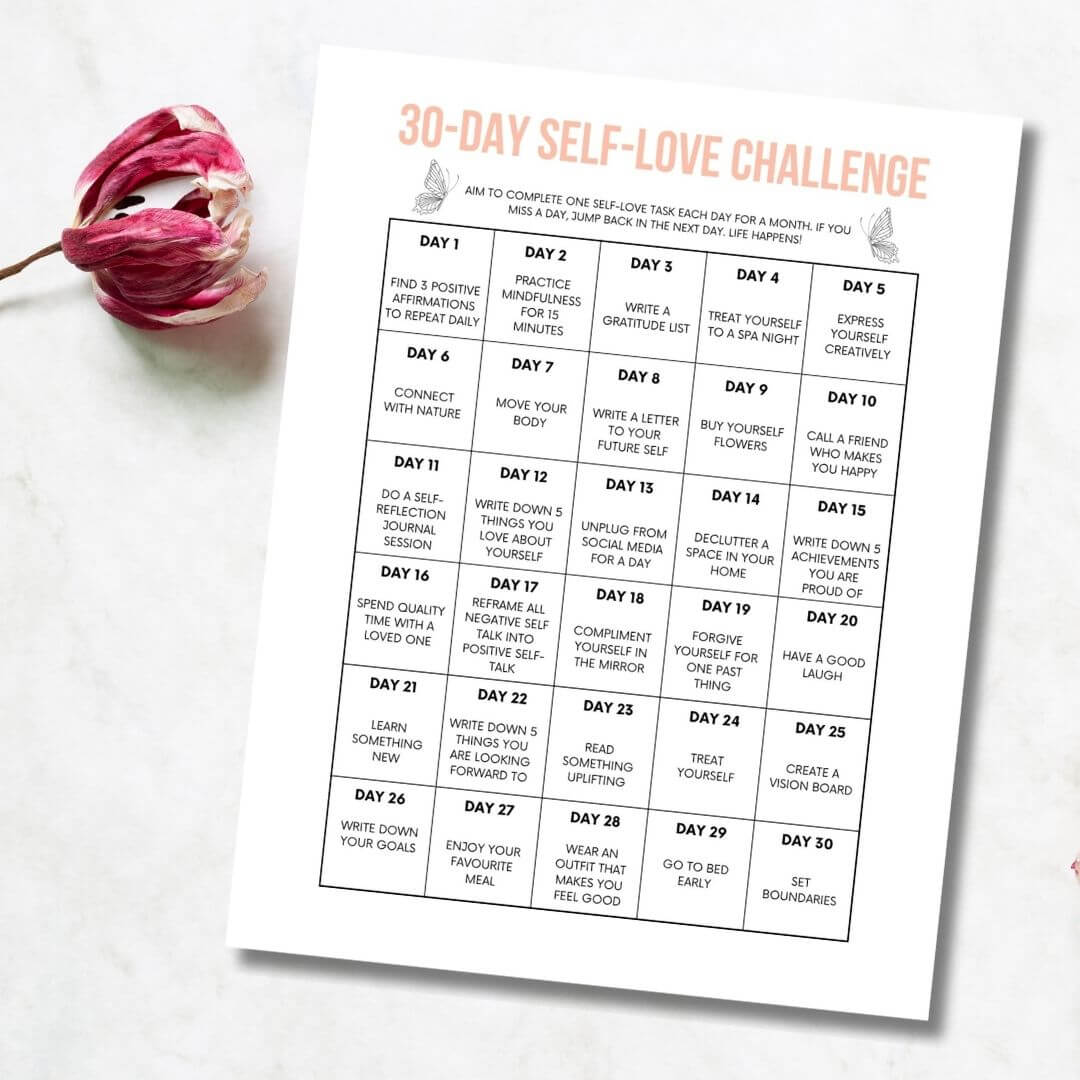 Printable 30 day self-love challenge calendar on a white surface with a flower.
