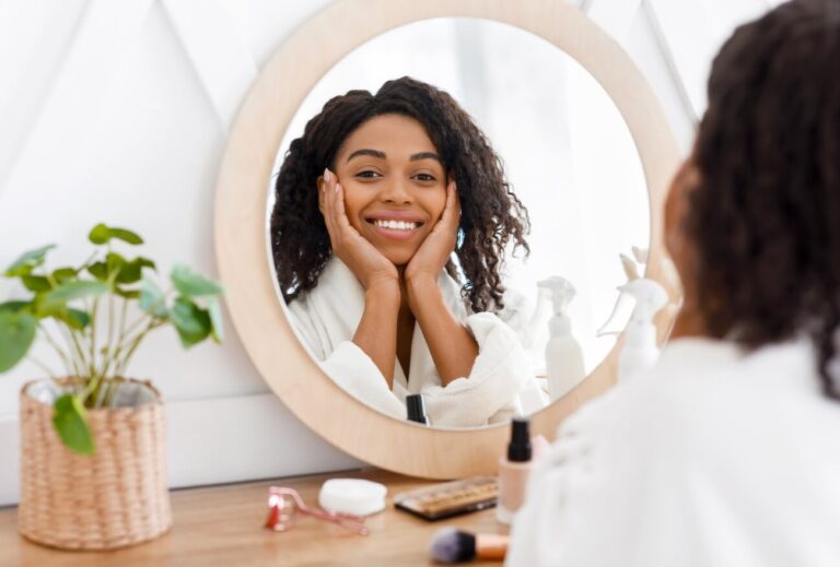 happy african american woman sitting in front of mirror applying face care.