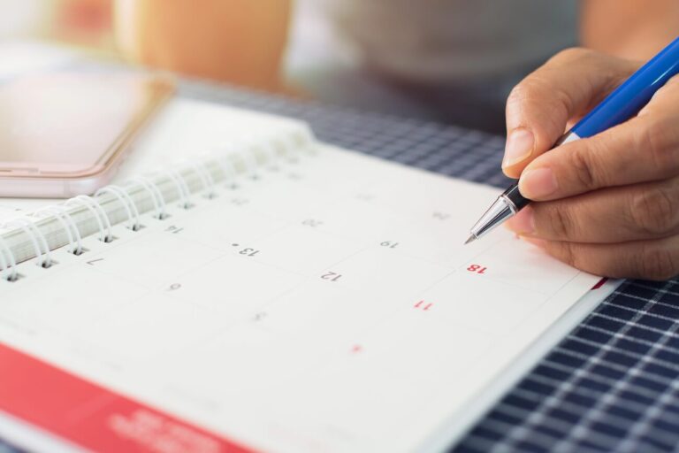 woman writing on planner calendar.