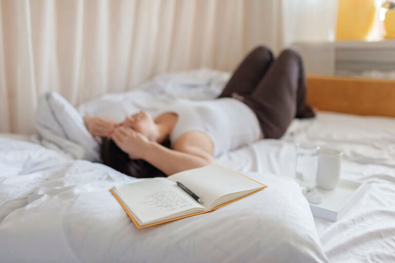 woman laying on bed after journaling.