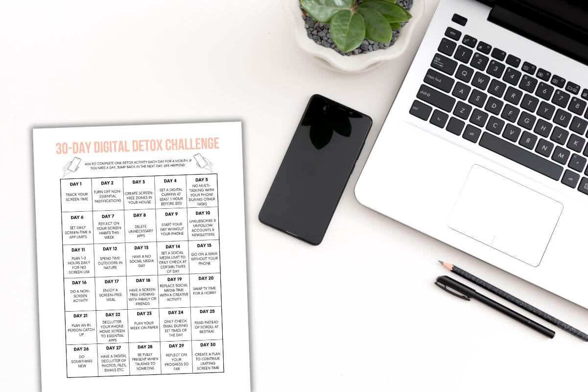 30 day digital detox challenge printable on desk with phone and laptop.