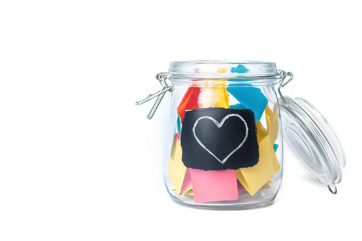 glass jar with lid filled with folded coloured notes.